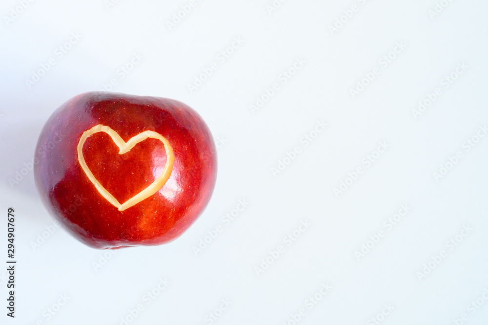 Beautiful bright juicy ripe red apple with a heart shaped cut-out, located in centre on a white background. space for text Beautiful bright juicy ripe red apple with a heart shaped cut-out, located in centre on a white background. space for text