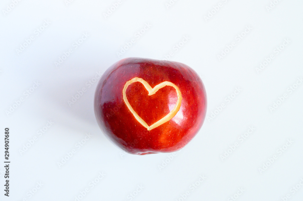 Beautiful bright juicy ripe red apple with a heart shaped cut-out, located in centre on a white background. Beautiful bright juicy ripe red apple with a heart shaped cut-out, located in centre on a white background.