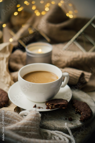 Cup of coffe with milk and chocolate cookies on warm wool blanket, cozy winter home