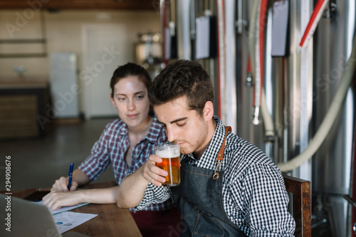 Young entrepreneurs working at a brewery testing beer photo