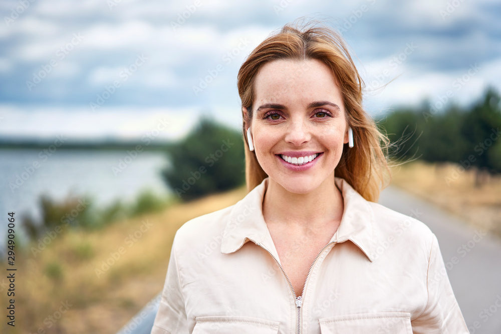 Portrait of smiling woman with wireless earphones in nature Portrait of smiling woman with wireless earphones in nature
