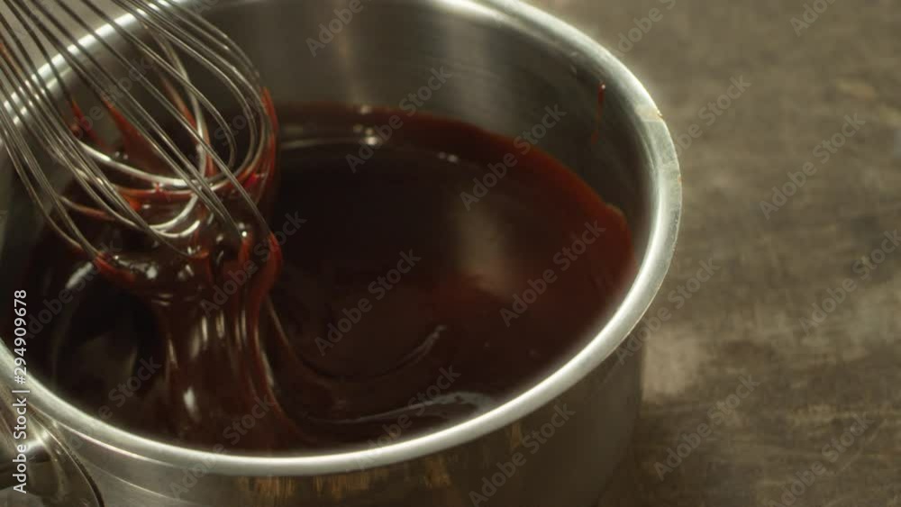 Closeup of liquid chocolate in bowl mixing with whisk in slow motion. Closeup of liquid chocolate in bowl mixing with whisk in slow motion.