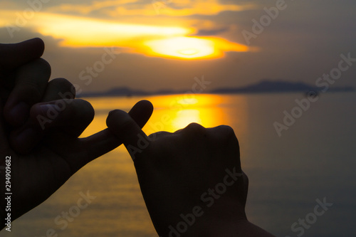 Obraz na plátně Silhouette of hand to pinky promise, pinky swear in front of the sun during sunset time