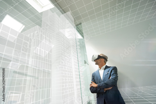 Businessman wearing VR goggles, looking at virtual architecture photo