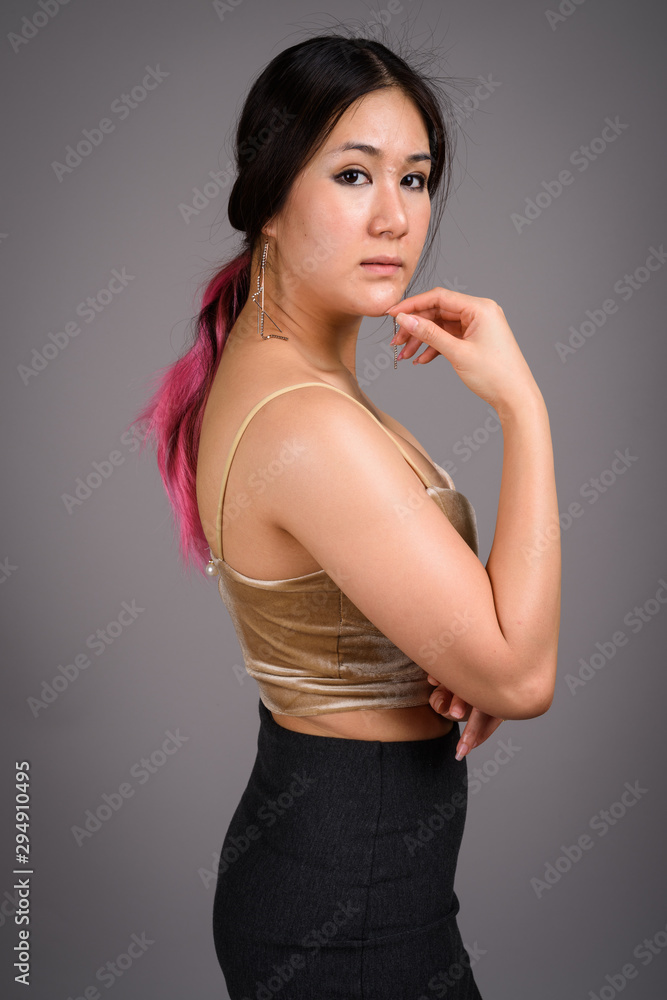 Young beautiful Asian woman against gray background Young beautiful Asian woman against gray background