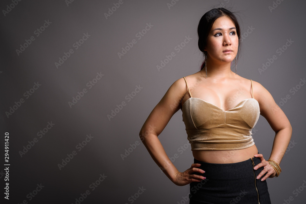 Young beautiful Asian woman against gray background Young beautiful Asian woman against gray background