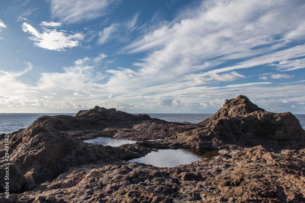 piedras volcánicas con mar adentrándose y nubes blancas piedras volcánicas con mar adentrándose y nubes blancas