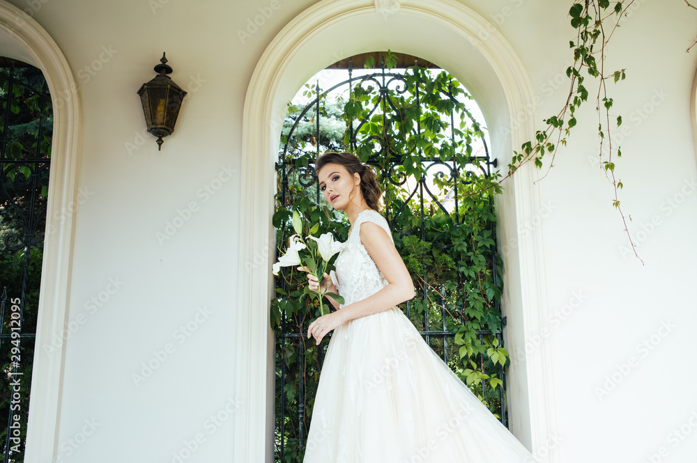 Fototapeta premium Beautiful bride with wedding flowers bouquet, attractive woman in wedding dress. Happy newlywed woman. Bride with wedding makeup and hairstyle. Smiling bride. Wedding day. Gorgeous bride. Marriage.