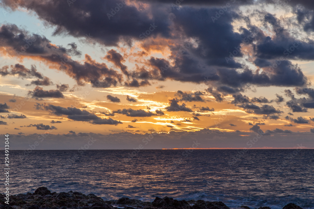 Fototapeta premium atardecer en salinas de Agaete con cielo naranja y nubes