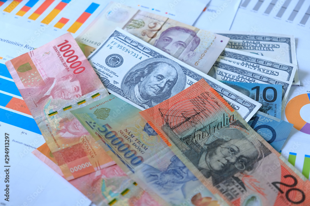 Obraz premium Business and Financial Concept. Multiple Currencies Banknote with laptop on graph and chart.