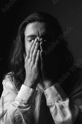 Sad young man with long hair. Black and white.