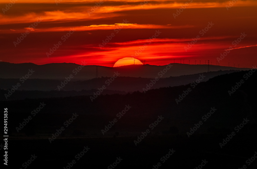 Sunrise over the horizon with windmills and red sky