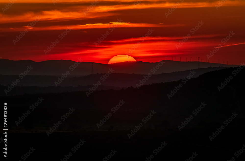 Sunrise over the horizon with windmills and red sky Sunrise over the horizon with windmills and red sky