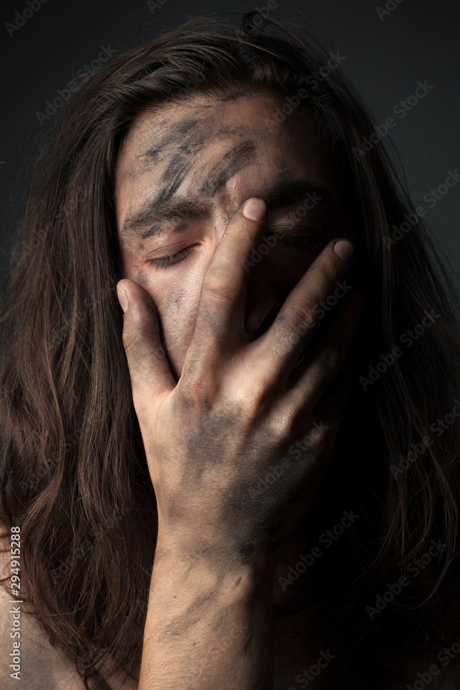 Portrait of a unhappy young man in soot. Hand on face Portrait of a unhappy young man in soot. Hand on face