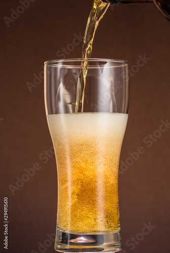 Wallpaper Mural Full narrow glass of beer with foam on an orange brown background Torontodigital.ca