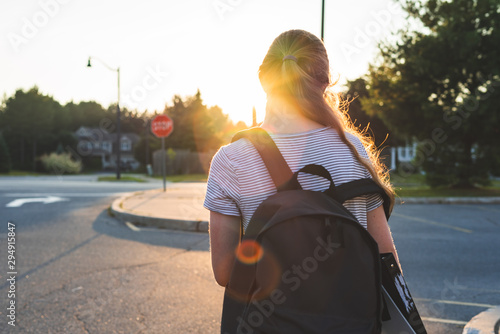 Tableau sur toile Profile of a teen girl depressed/sad at sunset in a parking lot while wearing a backpack and holding binders