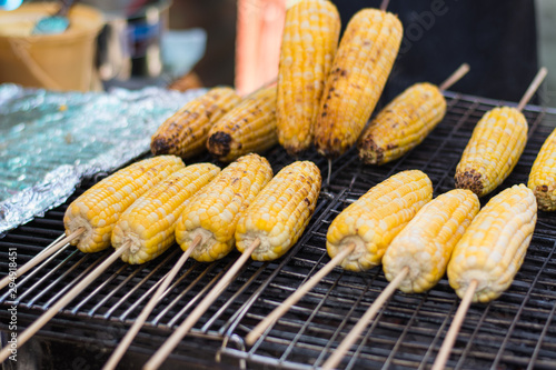 Grilled sweet corn on skewer with some corn burnt