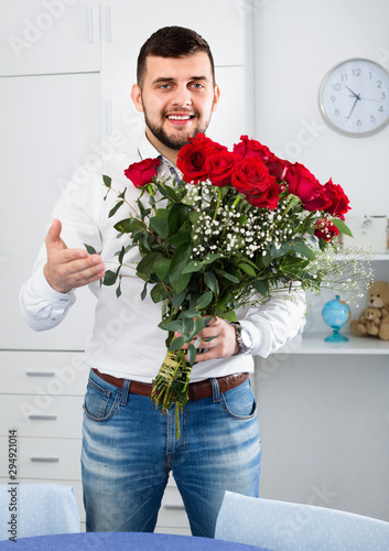 Fototapete Young man ready to present flowers to woman