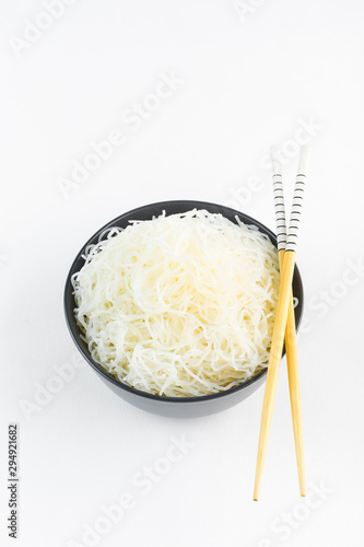 Cellophane rice noodles in a black bowl with chopsticks on white background, isolate, top view photo