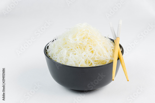 Cellophane rice noodles in a black bowl with chopsticks on white background, isolate, side view, closeup. photo