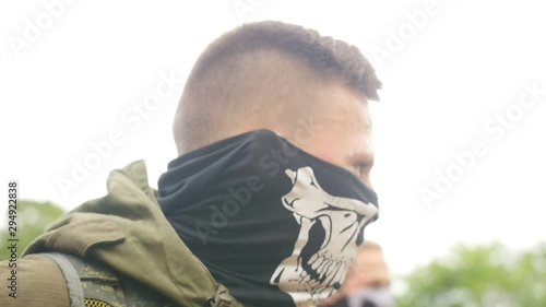 Portrait of young soldier in military uniform with cloth mask on his face. Sports game using a copy of a firearm. Close up shot.