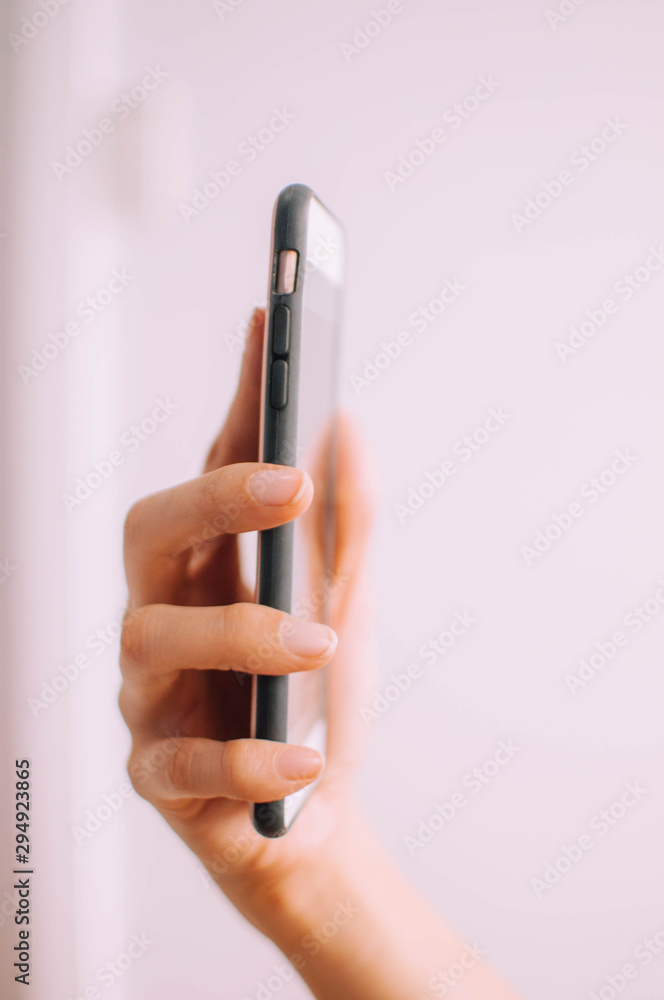 A close-up view of a young person's hand using a mobile phone on a white background A close-up view of a young person's hand using a mobile phone on a white background