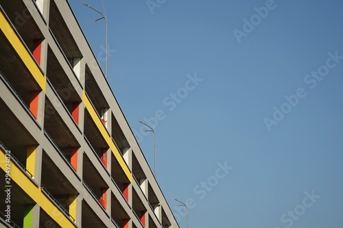 facade of multi-level colored parking with vertical decorative panels against the blue clear sky, the frame from the bottom up