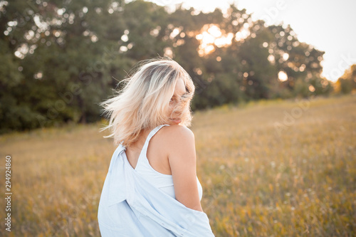 Young woman in shirt walking outdoors under sunset light. Turn
