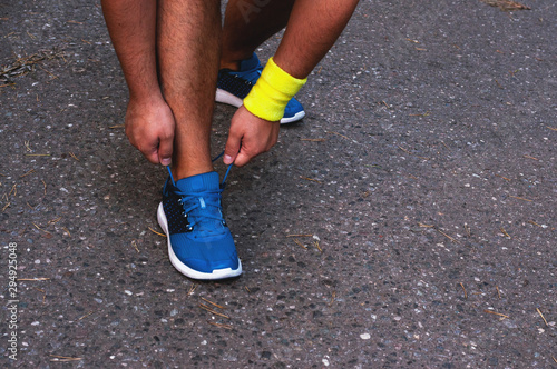 Young tanned male runner tying shoelaces, getting ready for a run. The concept of a healthy lifestyle, freedom