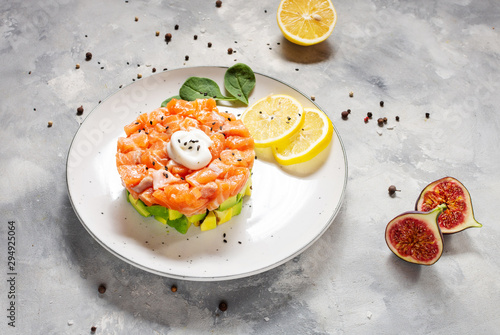 Delicious avocado and salmon tartar on concrete background