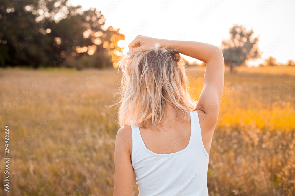 Young woman in white shirt looking on the sunset. Back Young woman in white shirt looking on the sunset. Back