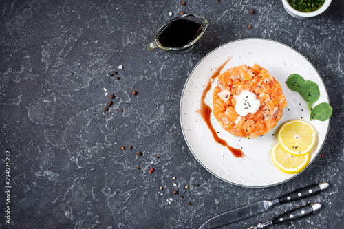 Delicious avocado and salted salmon tartar on black stone background