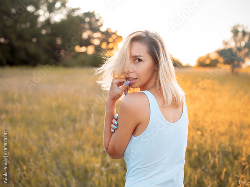 Beautiful young woman in white shirt walking outdoors at sunset. Turn around.
