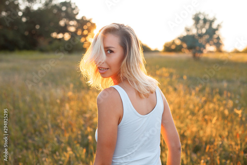 Young woman walking on the field at sunset. Turn around