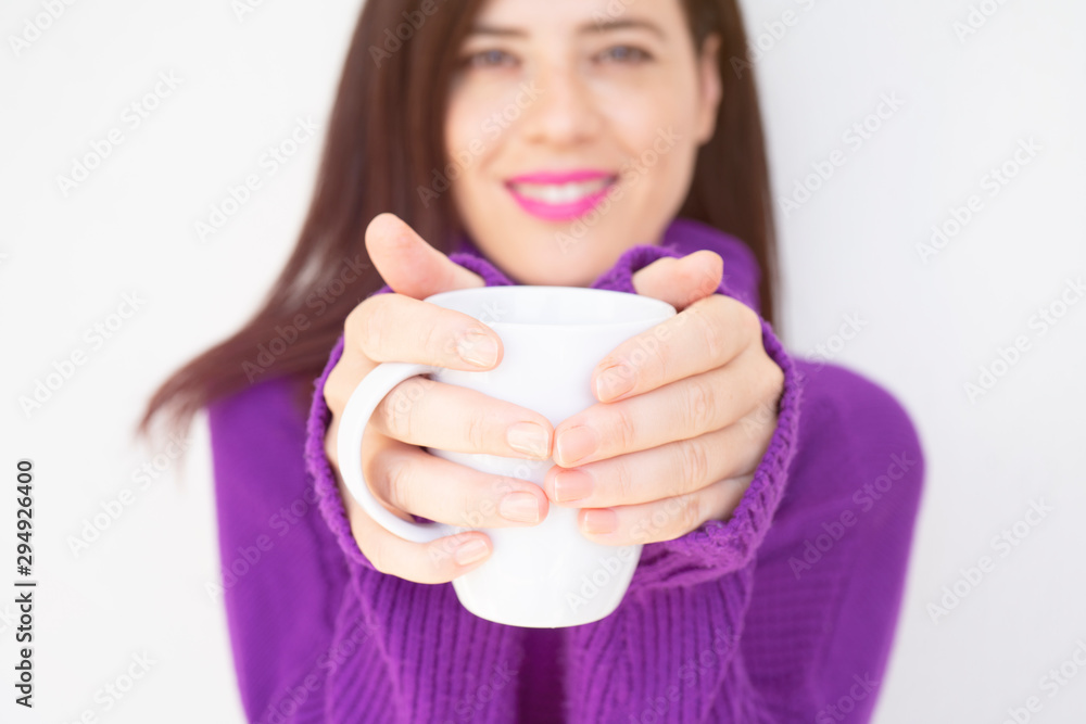 Close up of a beautiful young woman holding a cup of hot coffee in winter outfit at home Close up of a beautiful young woman holding a cup of hot coffee in winter outfit at home