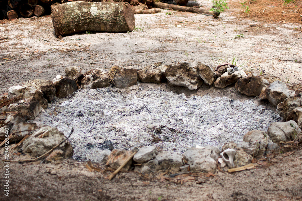 Fototapeta premium A stone circle fire pit filled with ash from recent fire.