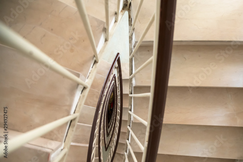 closeup view spiral staircase with marble steps and wooden handrail