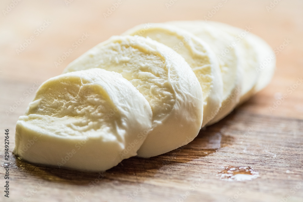 Slices of water buffalo cheese mozzarella on wood background.