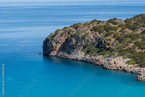 Fototapeta Naklejka Na Ścianę i Meble -  Sea landscape. Island and 2 people in a boat. Blue water.