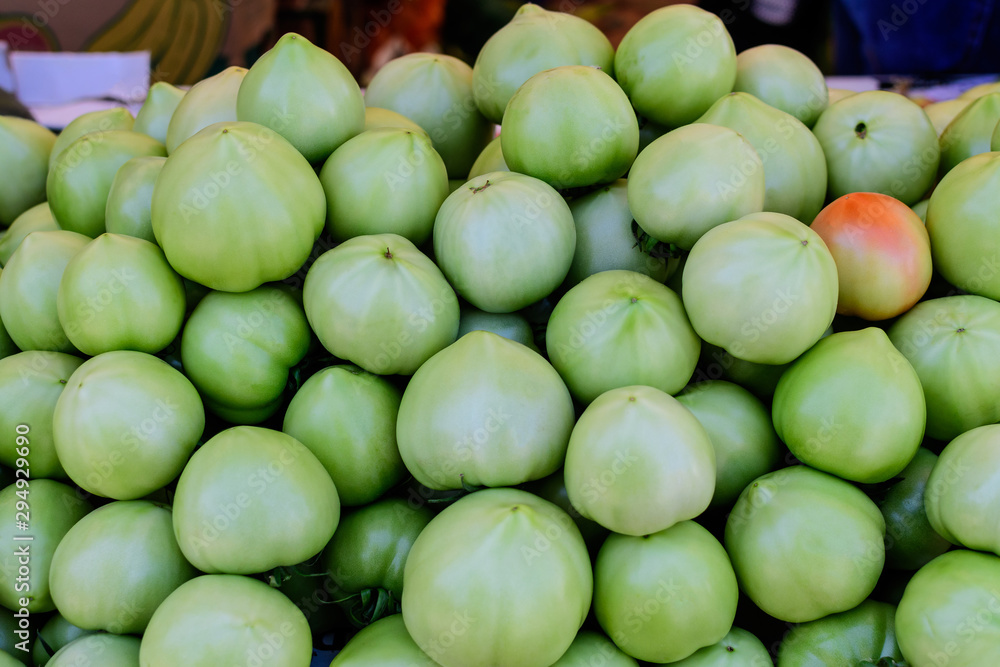 Group of fresh raw green tomatoes available for sale at a street food market, natural background, soft focus Group of fresh raw green tomatoes available for sale at a street food market, natural background, soft focus