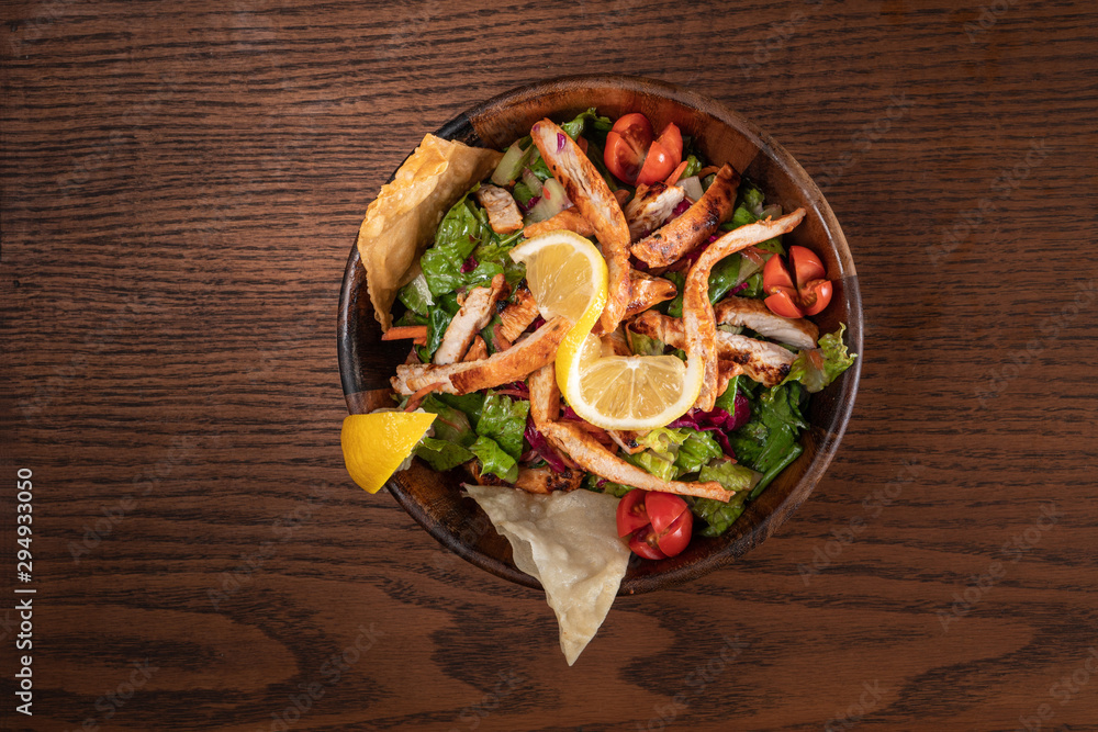 Healthy chicken salad with red cabagge and tomato isolated on rustic wooden kitchen table