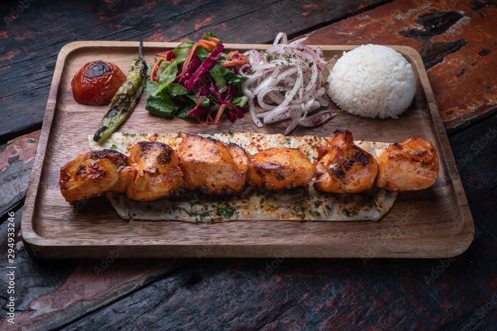 Turkish chicken sis kebab with rice and vegetables isolated on rustic wooden table Turkish chicken sis kebab with rice and vegetables isolated on rustic wooden table