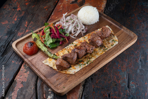 Turkish lamb sis kebab with rice and vegetables isolated on rustic wooden table