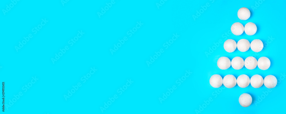Banner. Silhouette of a Christmas tree made of white New Year's toys on a blue background. Creative decoration. Banner. Silhouette of a Christmas tree made of white New Year's toys on a blue background. Creative decoration.