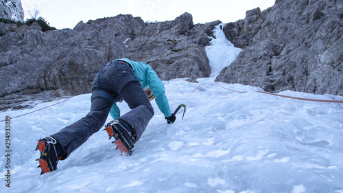 Schilderij op canvas BOTTOM UP: Woman ice climbing in the Julian Alps stops and looks at her crampons