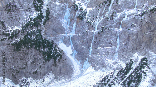 AERIAL Flying towards a rocky cliff and frozen waterfalls in Slovenian mountains