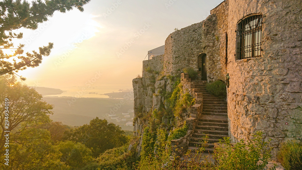 Golden evening sunbeams shine on an old medieval castle in the Slovenian seaside
