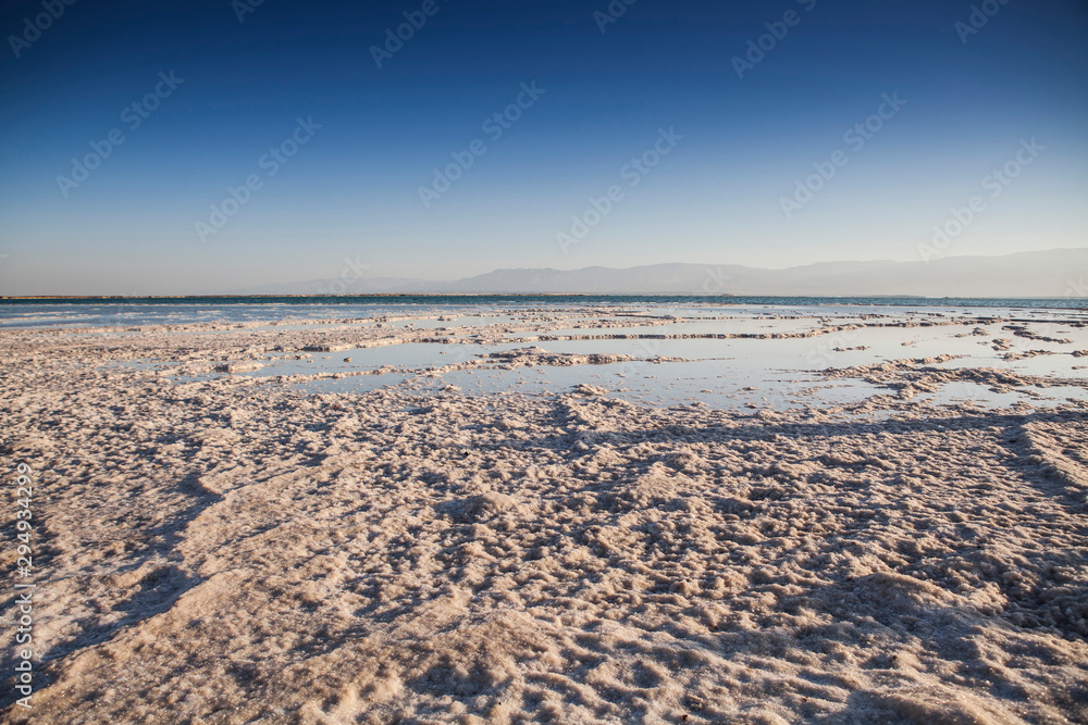 Dead sea landscape with blue sky and seafront full of salt 