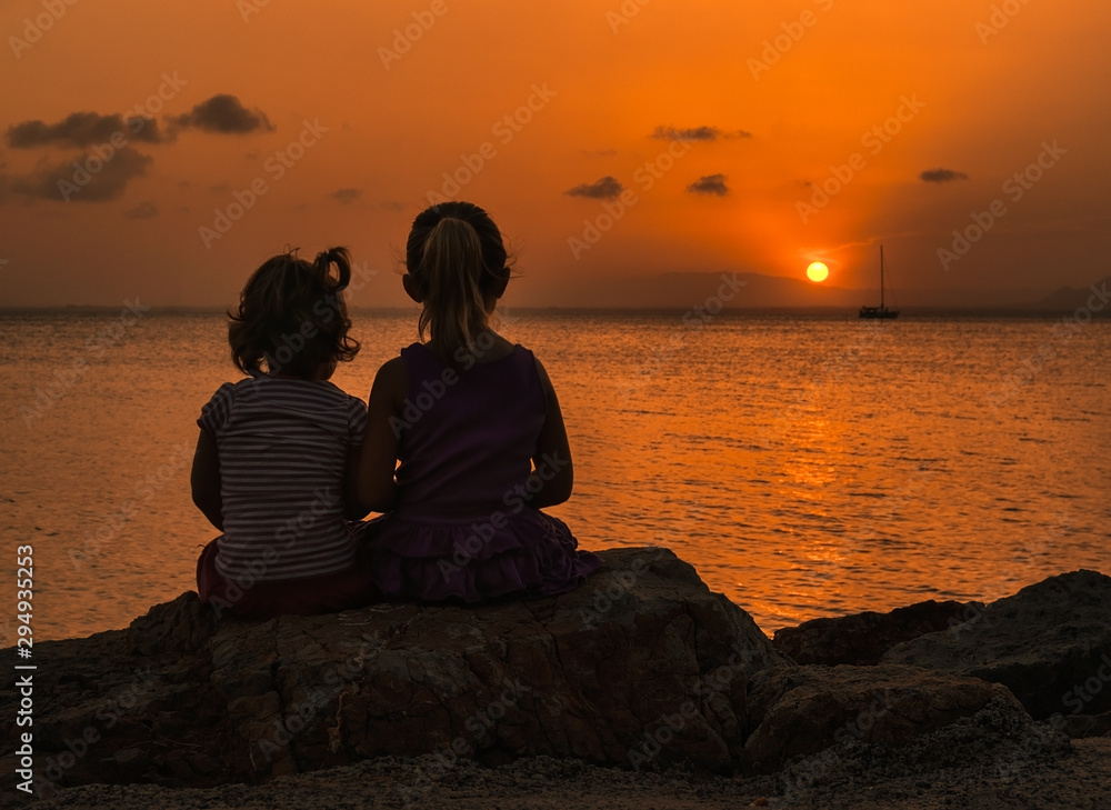 Sisters bathed in the rays of the sun that disappears on the horizon Sisters bathed in the rays of the sun that disappears on the horizon