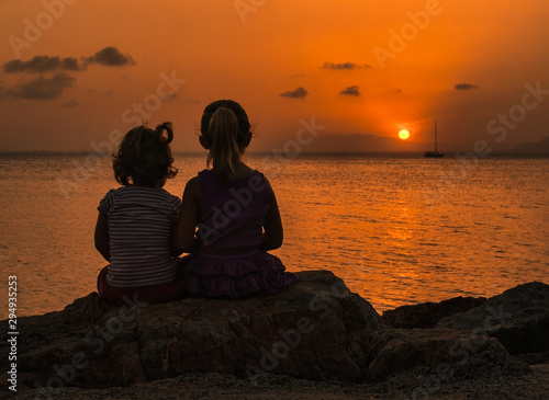 Sisters bathed in the rays of the sun that disappears on the horizon photo